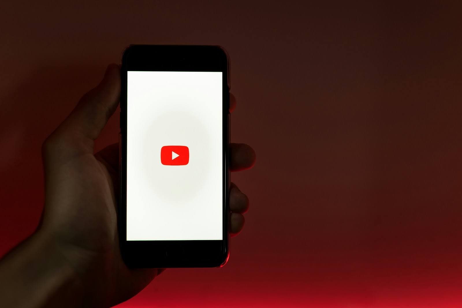 Hand holding up a phone with the YouTube app being opened